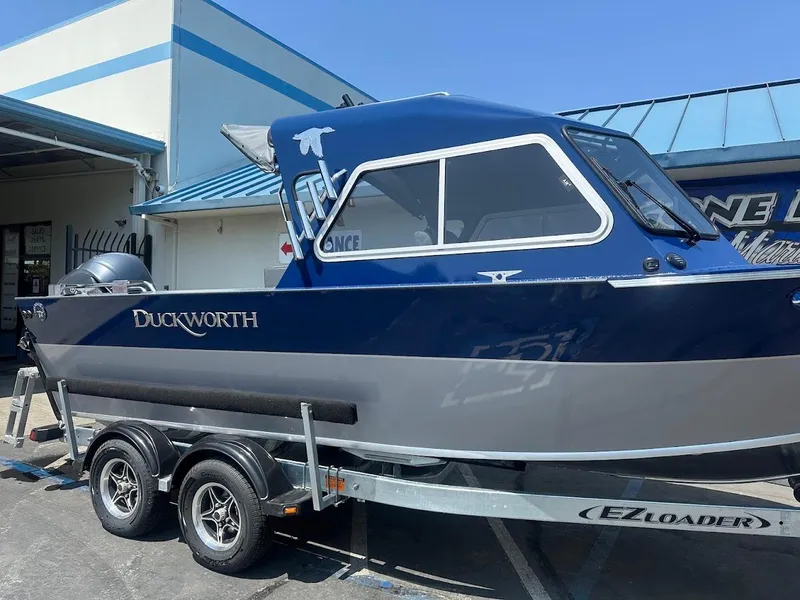 Slide: The Image of 2025 Duckworth 21 Discovery boat on EZ Loader trailer, parked outside a building. - 3