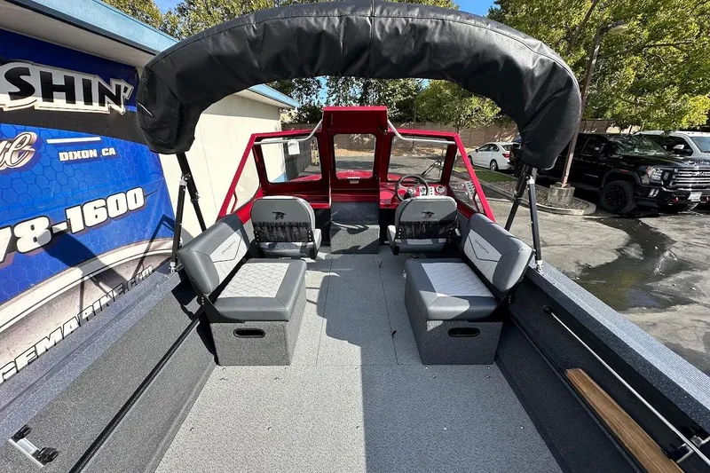 Slide: The Image of 2025 Duckworth 20 Advantage SE boat interior with seating and canopy, parked outdoors. - 12