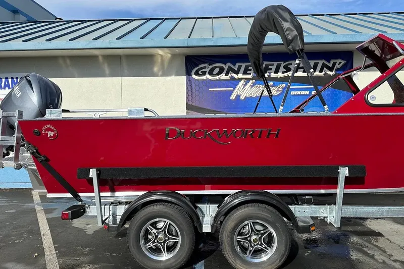 Slide: The Image of Red 2025 Duckworth 20 Advantage SE boat on trailer, parked outside a marine store. - 7