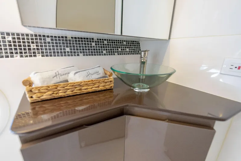 Slide: The Image of Modern bathroom vanity with glass sink, mosaic backsplash, and wicker basket. Hanover 415, 2024 model. - 6