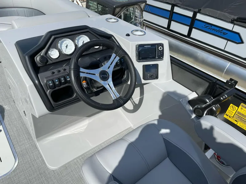 Slide: The Image of 2025 Bentley Pontoons Legacy 243 QSB helm with modern controls and dual captain seating. - 16