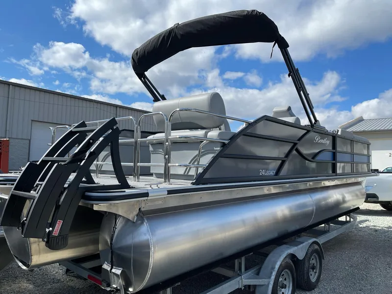 Slide: The Image of 2025 Bentley Pontoons Legacy 243 QSB Dual Captain Full Tube on trailer, under blue sky. - 2