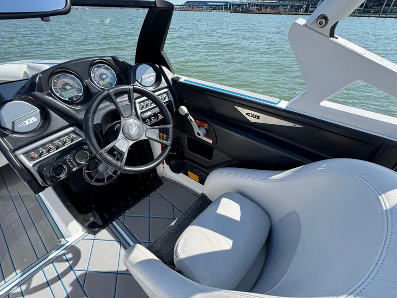 Slide: The Image of 2015 Axis A22 boat interior with steering wheel and dashboard, overlooking water. - 10