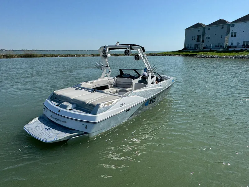 Slide: The Image of 2015 Axis A22 boat on calm water near shoreline buildings. - 4