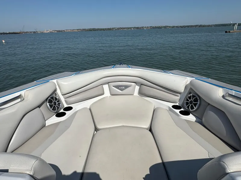 Slide: The Image of 2015 Axis A22 boat interior with cushioned seating and cup holders on a calm lake. - 6