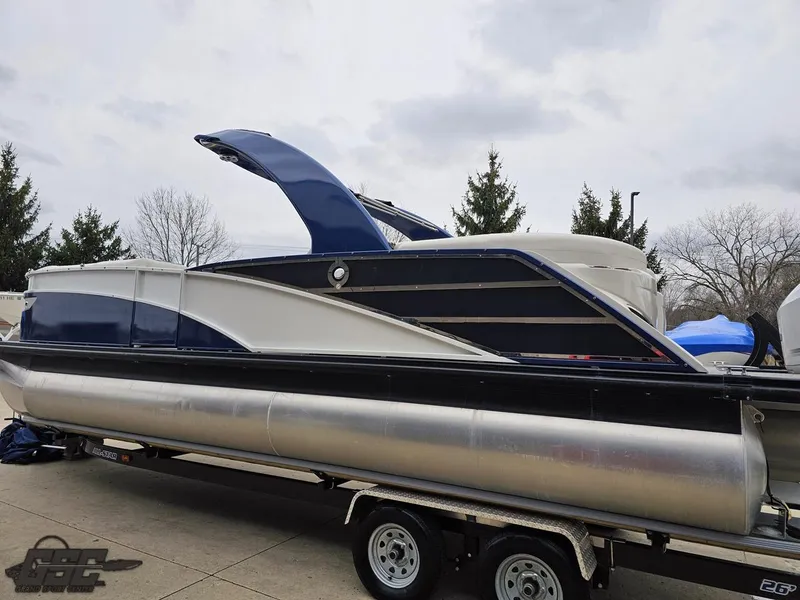 Slide: The Image of 2021 Bennington RX 25 Quad Bench pontoon boat on trailer, parked outdoors. - 25