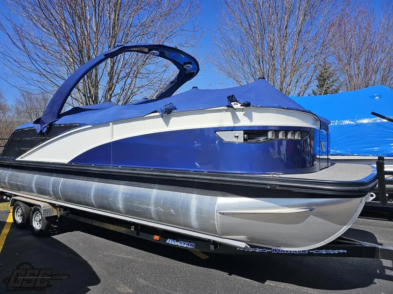 Slide: The Image of 2021 Bennington RX 25 Quad Bench pontoon boat with blue cover on trailer. - 4
