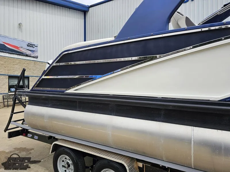 Slide: The Image of 2021 Bennington RX 25 Quad Bench pontoon boat on trailer, parked outside a building. - 8