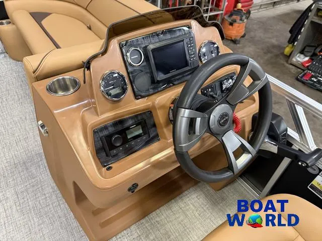 Slide: The Image of 2025 Tahoe Sport 2385 Tritoon dashboard with steering wheel and controls, featuring Boat World logo. - 11