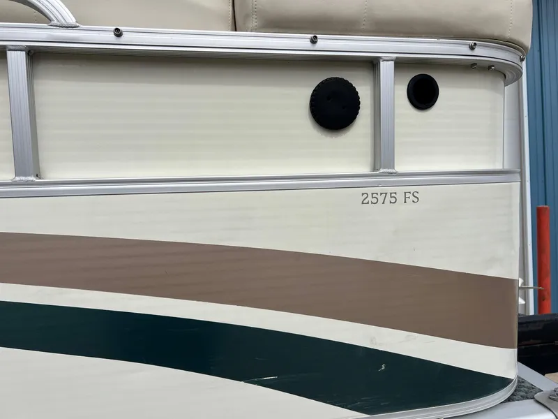 Slide: The Image of 2002 Bennington 2575 FS boat side view with beige and green accents. - 11