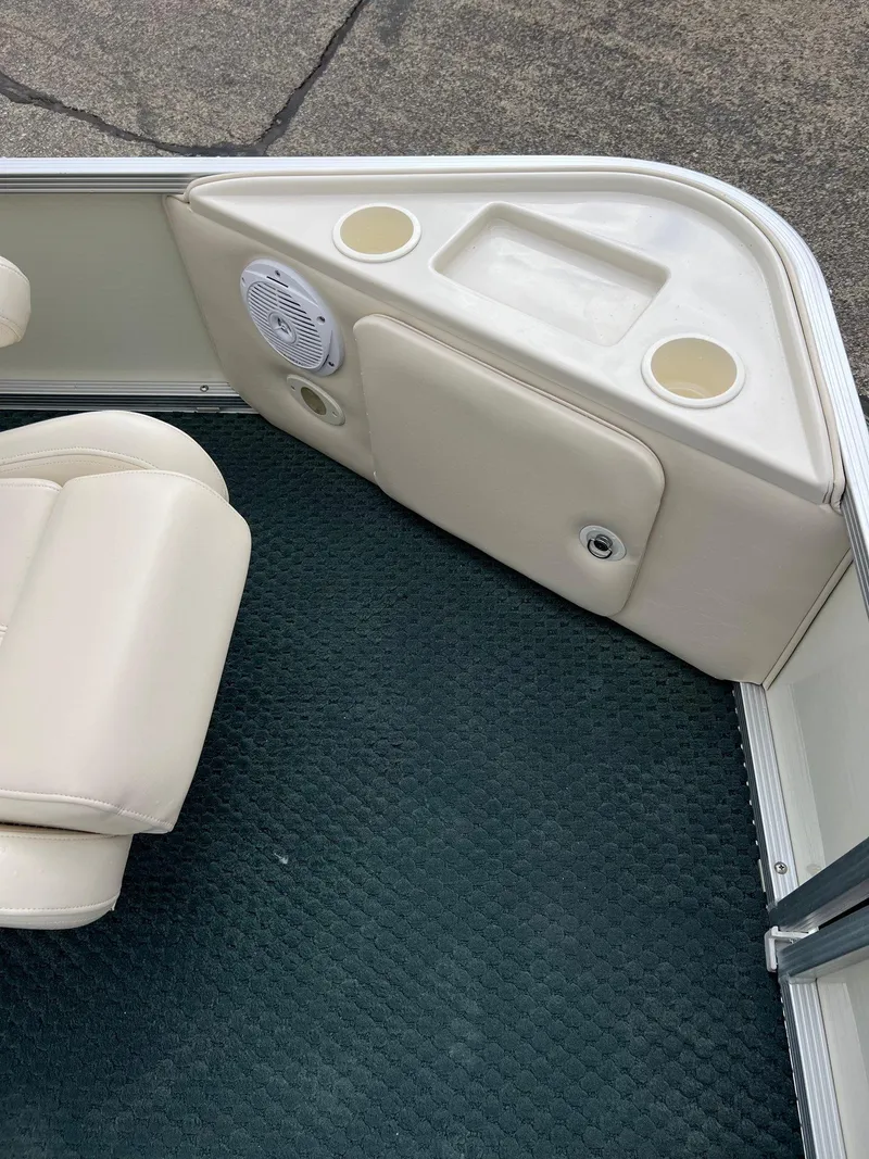 Slide: The Image of 2002 Bennington 2575 FS boat interior with beige seating, cup holders, and speaker. - 12
