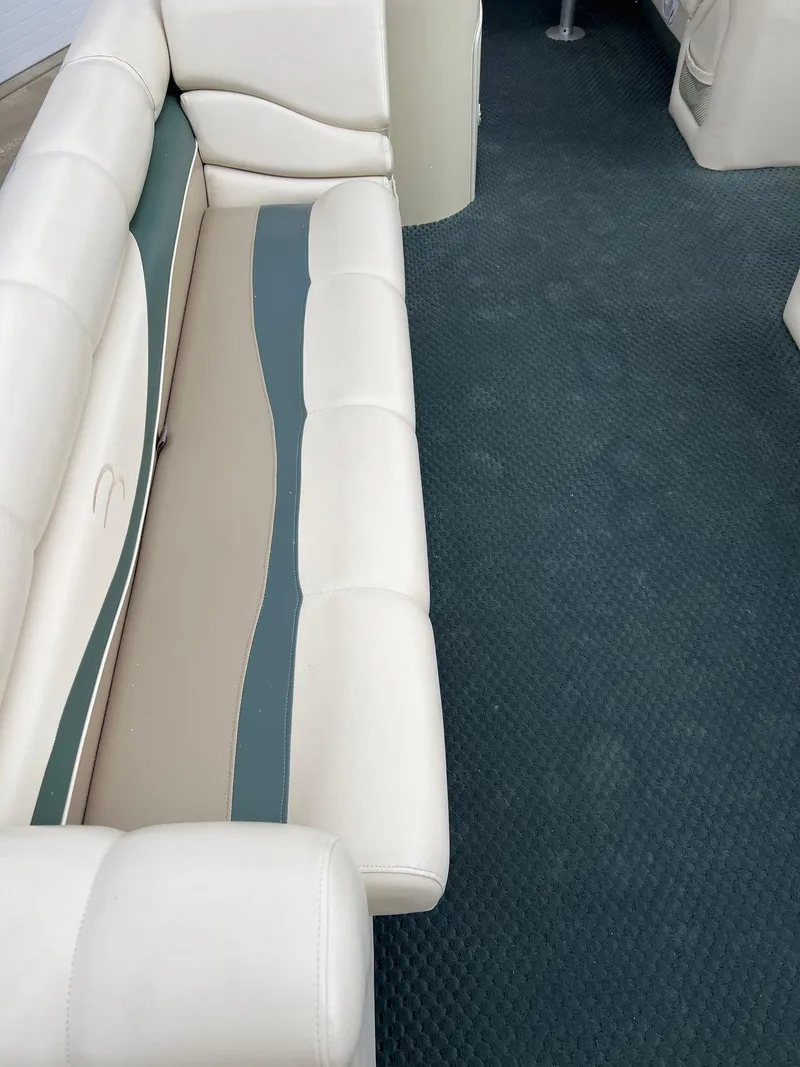 Slide: The Image of 2002 Bennington 2575 FS boat interior with beige and teal seating, blue carpet. - 18