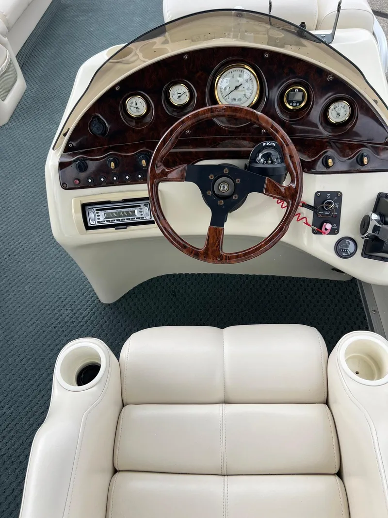 Slide: The Image of 2002 Bennington 2575 FS boat dashboard with wood-trimmed steering wheel and white seating. - 26