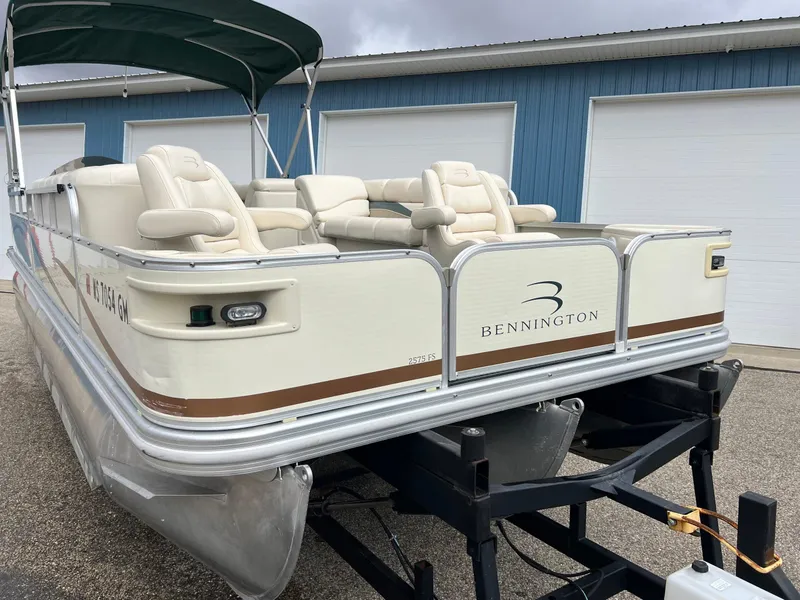 Slide: The Image of 2002 Bennington 2575 FS pontoon boat with beige seating and canopy, parked on a trailer. - 6