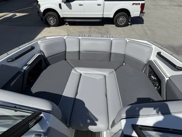 Slide: The Image of 2025 Moomba Max boat interior with gray seating, parked near a white truck. - 10