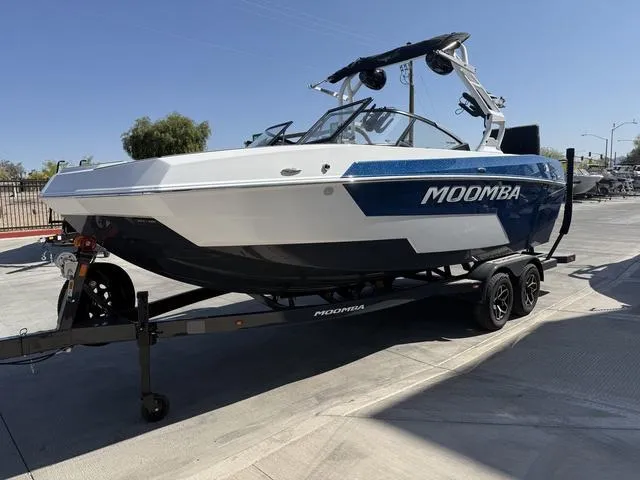 Slide: The Image of 2025 Moomba Max boat on trailer, blue and white design, parked outdoors. - 4