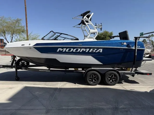 Slide: The Image of 2025 Moomba Max boat on trailer, blue and white design, parked outdoors. - 5