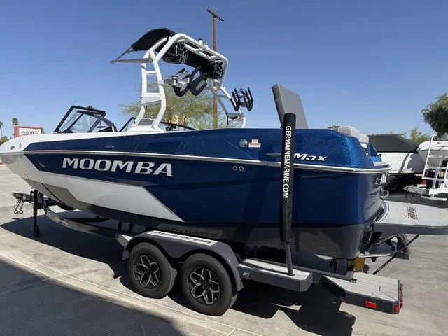 Slide: The Image of 2025 Moomba Max boat on trailer, blue and white design, parked outdoors. - 6