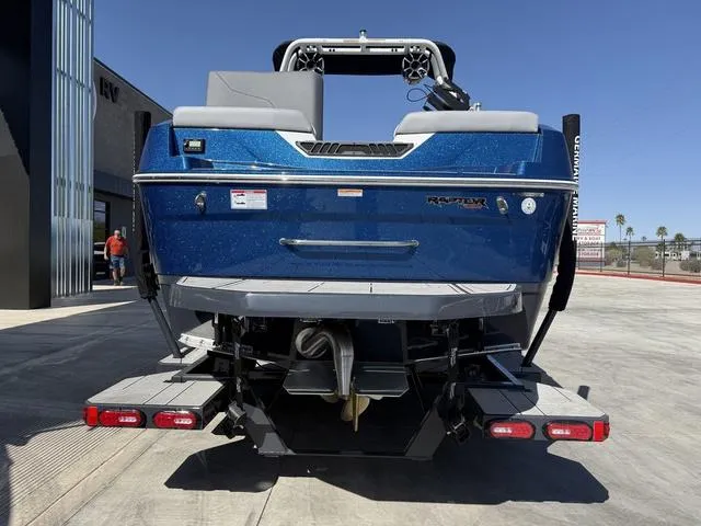Slide: The Image of 2025 Moomba Max boat rear view, blue exterior, parked outdoors. - 7