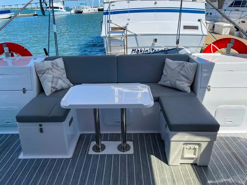 Slide: The Image of Seawind 1260 catamaran 2023 model with outdoor seating and table, docked at marina. - 10