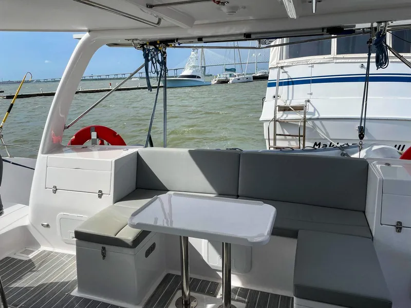 Slide: The Image of 2023 Seawind 1260 catamaran cockpit with seating and table, docked near other boats. - 17