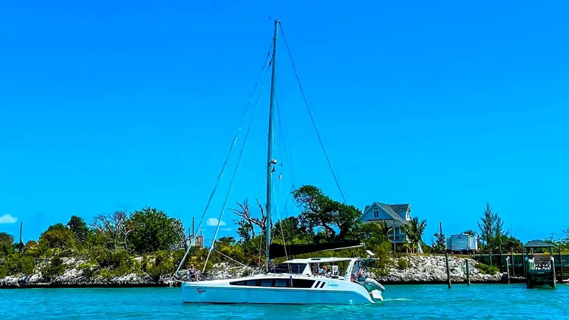 Slide: The Image of 2023 Seawind 1260 catamaran sailing near a coastal home under a clear blue sky. - 3