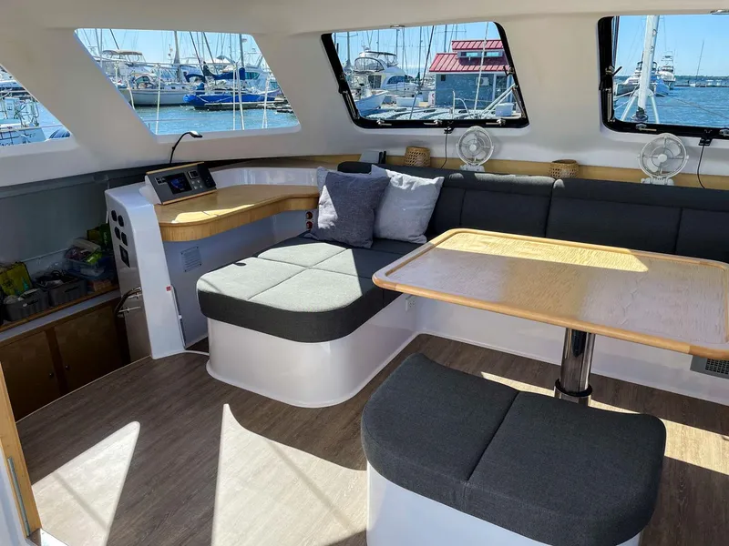 Slide: The Image of 2023 Seawind 1260 catamaran interior with modern seating and dining area, docked at marina. - 37