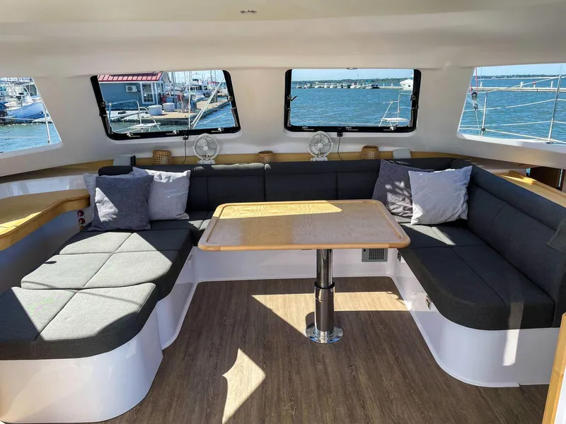 Slide: The Image of Interior of 2023 Seawind 1260 catamaran with spacious seating and table, overlooking marina. - 44
