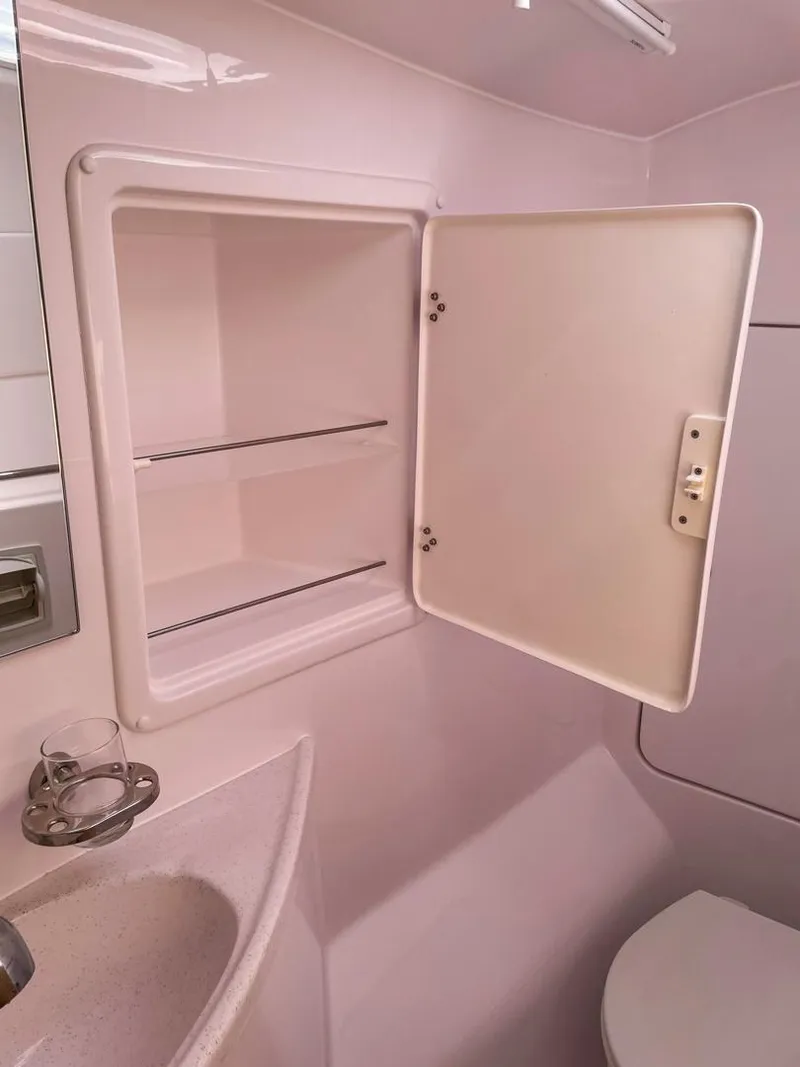 Slide: The Image of Seawind 1260 2023 bathroom cabinet with open door, sink, and toilet. - 51