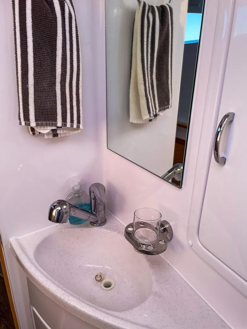 Slide: The Image of 2023 Seawind 1260 bathroom with sink, mirror, and striped towel. - 52