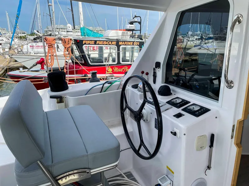Slide: The Image of Helm of 2023 Seawind 1260 catamaran with marina and fire rescue boat in background. - 7