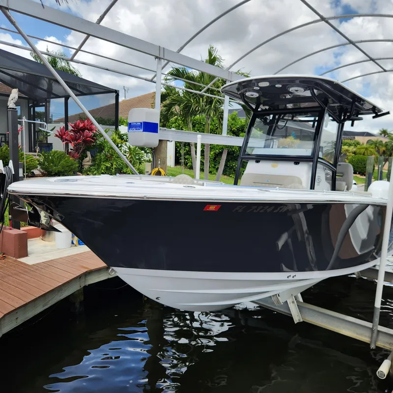 Slide: The Image of 2021 Sportsman Open 252 Center Console boat docked near a wooden deck. - 1