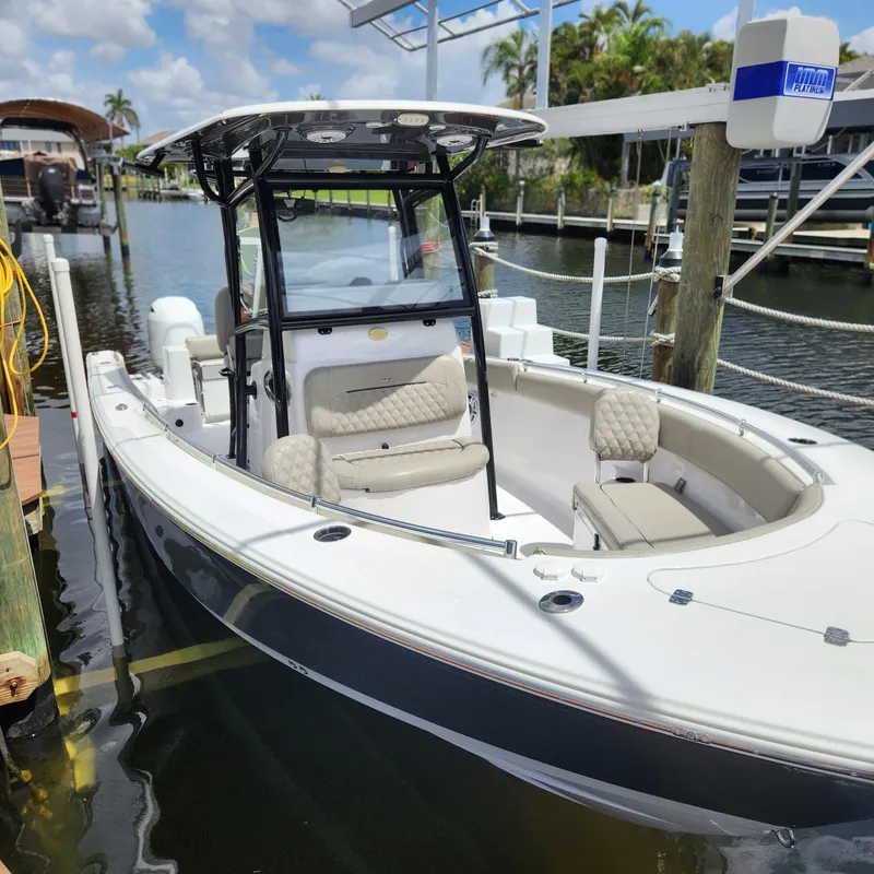 Slide: The Image of 2021 Sportsman Open 252 Center Console boat docked in a marina under a sunny sky. - 10