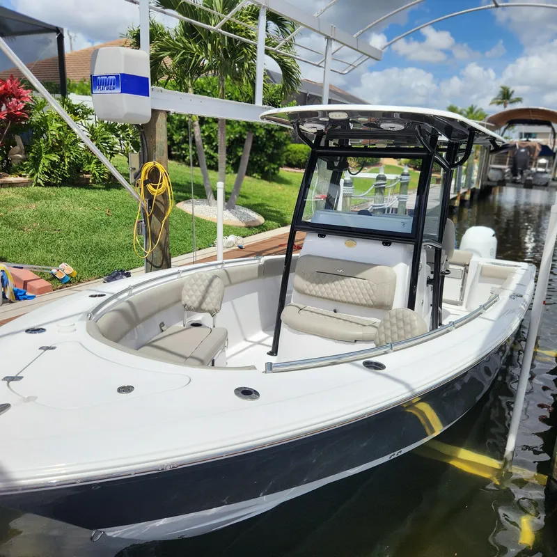 Slide: The Image of 2021 Sportsman Open 252 Center Console boat docked in a sunny marina setting. - 11
