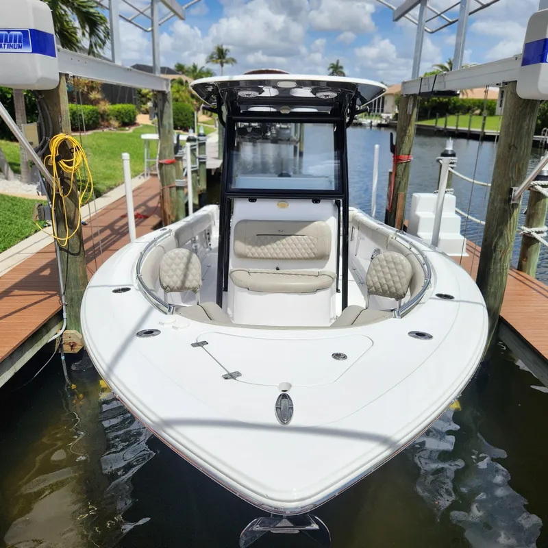 Slide: The Image of 2021 Sportsman Open 252 Center Console boat docked in a sunny marina. - 12