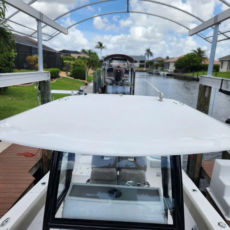 Slide: The Image of 2021 Sportsman Open 252 Center Console boat docked in a scenic canal setting. - 13