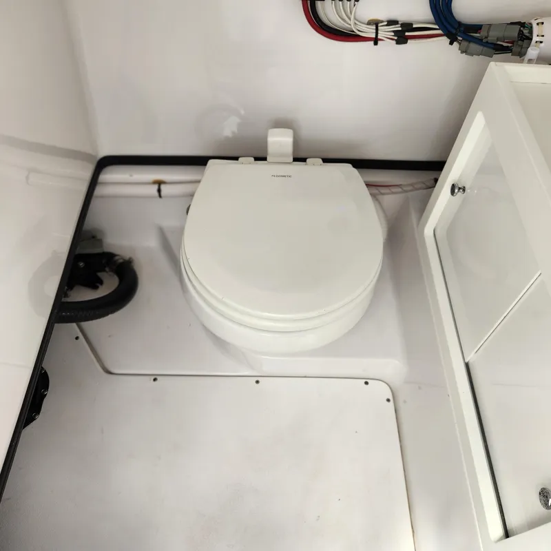Slide: The Image of 2021 Sportsman Open 252 Center Console boat interior with toilet and storage cabinet. - 19