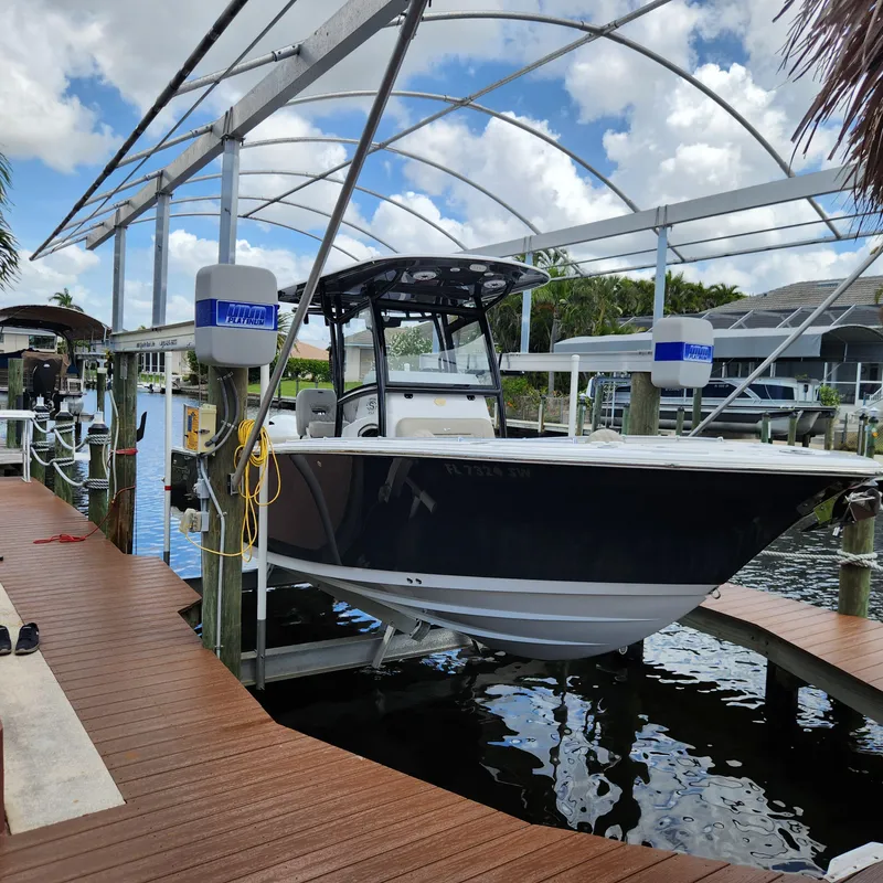 Slide: The Image of 2021 Sportsman Open 252 Center Console boat on a lift by a dock. - 2