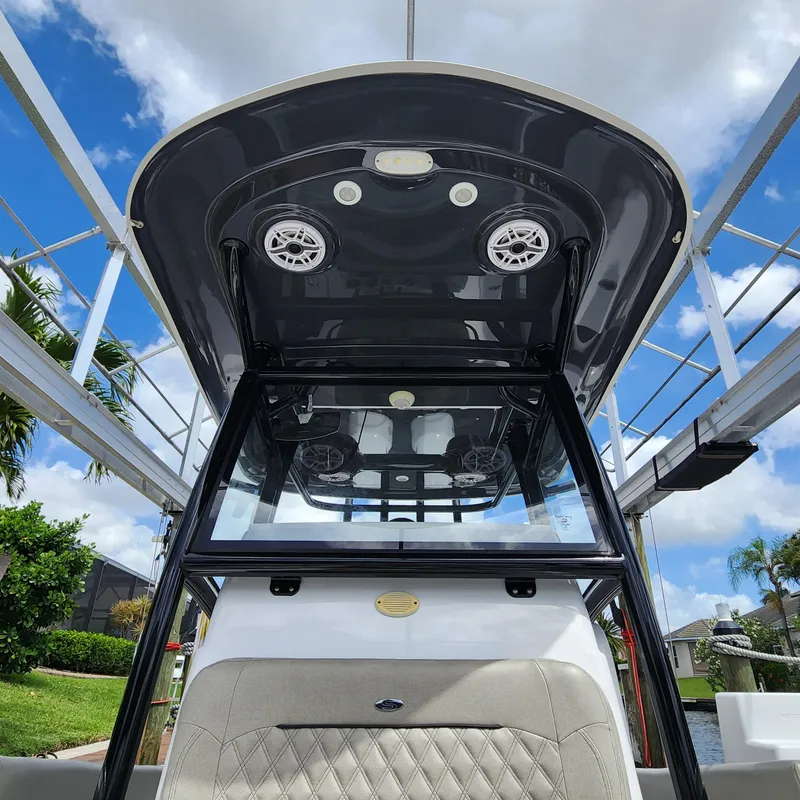 Slide: The Image of 2021 Sportsman Open 252 Center Console boat with T-top and speakers, under a blue sky. - 35