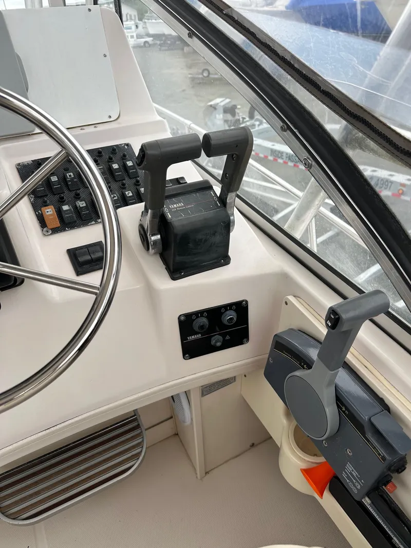 Slide: The Image of Control panel of a 2001 Grady-White Sailfish 282 boat, featuring steering wheel and throttle controls. - 18