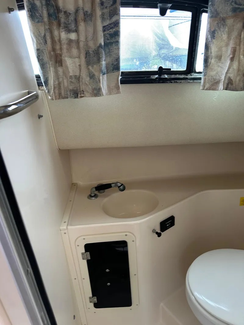 Slide: The Image of 2001 Grady-White Sailfish 282 boat bathroom with sink, toilet, and window curtains. - 26