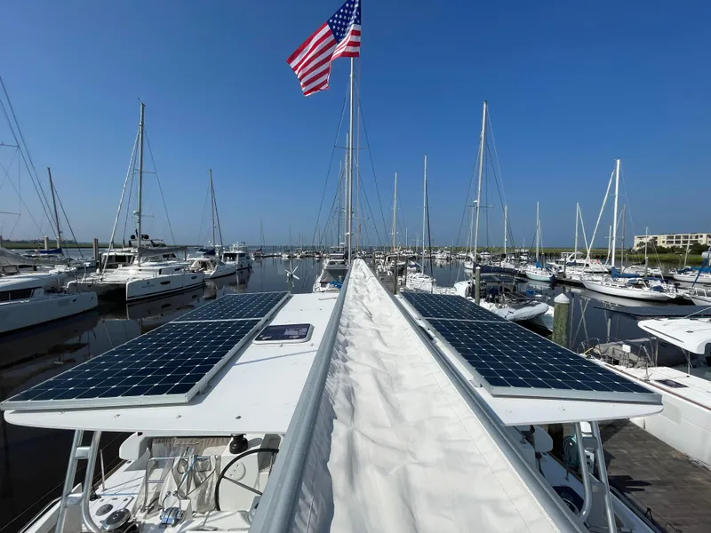 Slide: The Image of Lagoon 450 F catamaran with solar panels docked in marina, American flag flying, clear blue sky. - 34