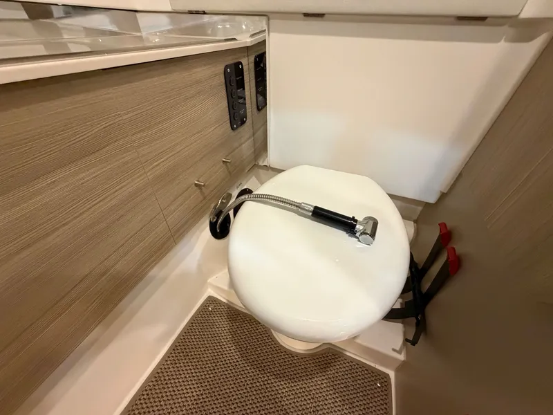 Slide: The Image of The image shows a modern boat toilet with wood paneling and a shower head. - 29
