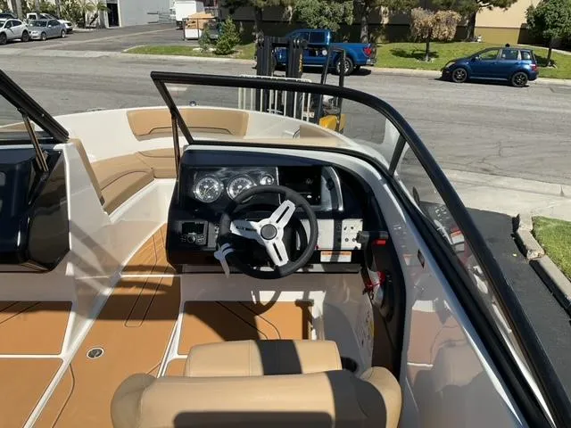Slide: The Image of 2025 Bayliner V20i boat interior with steering wheel and dashboard, parked in a residential area. - 15