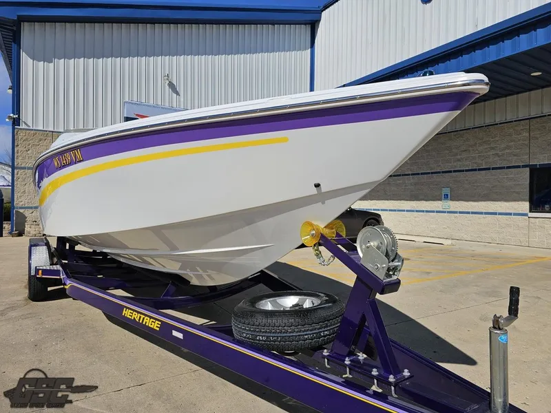 Slide: The Image of 2004 Baja 25 Outlaw boat on a trailer, white with purple and yellow accents. - 13