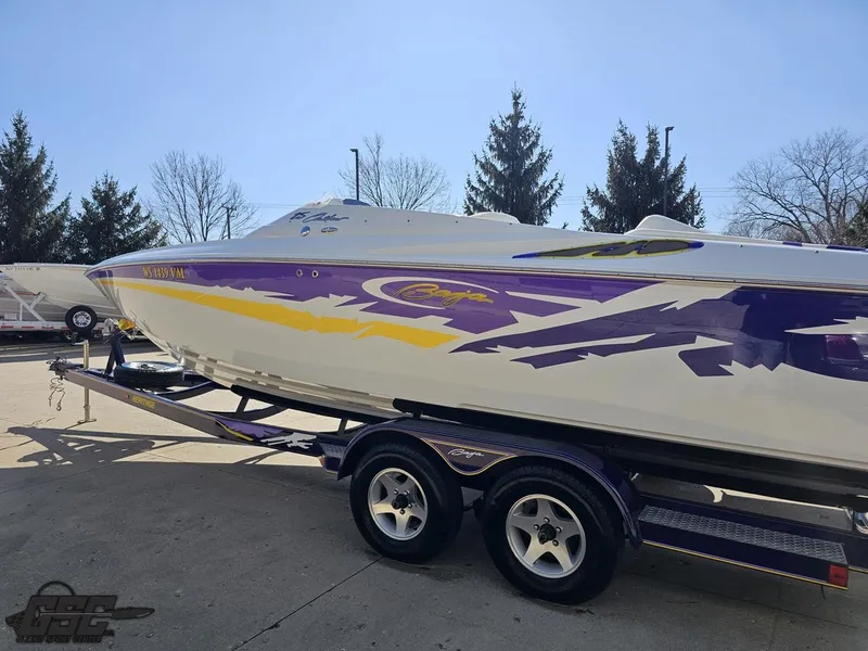 Slide: The Image of 2004 Baja 25 Outlaw speedboat with vibrant purple and yellow graphics on a trailer. - 22