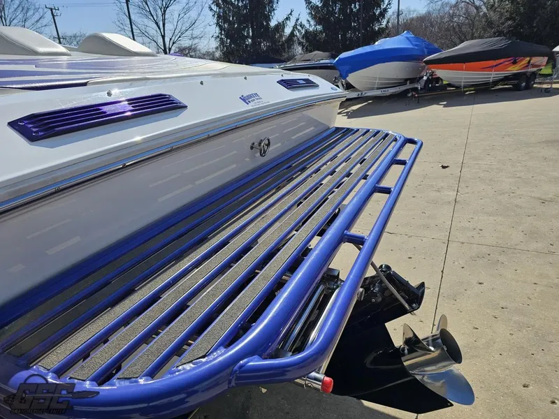 Slide: The Image of 2004 Baja 25 Outlaw boat with blue accents and propeller, parked outdoors. - 28