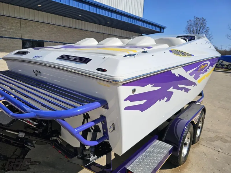 Slide: The Image of 2004 Baja 25 Outlaw speedboat with vibrant purple and yellow graphics on a trailer. - 32