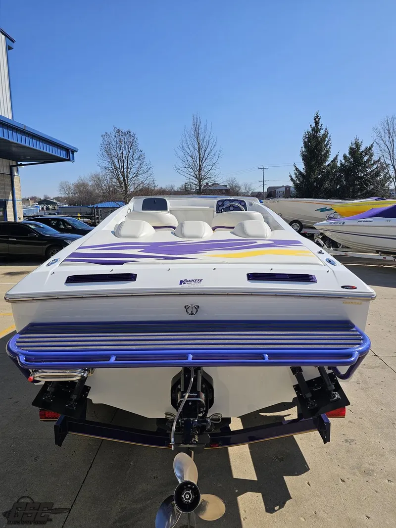 Slide: The Image of 2004 Baja 25 Outlaw speedboat with vibrant purple and yellow accents, docked outdoors. - 34