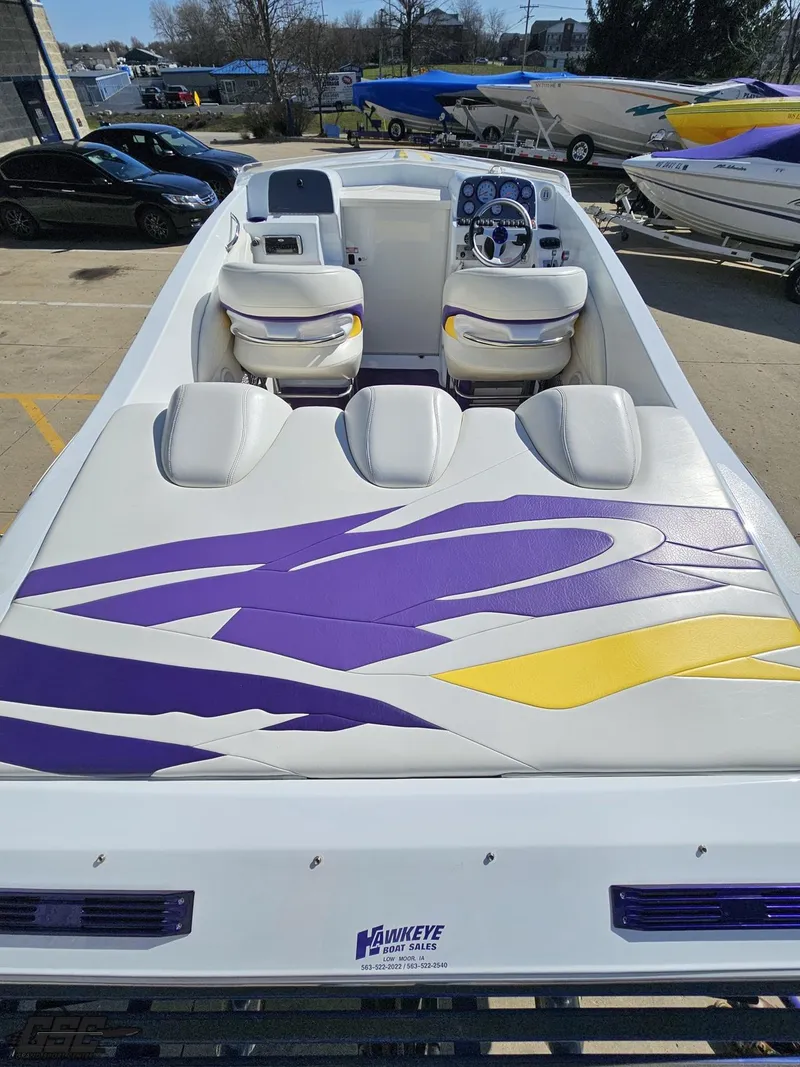 Slide: The Image of 2004 Baja 25 Outlaw boat with purple and yellow design, docked outdoors. - 38